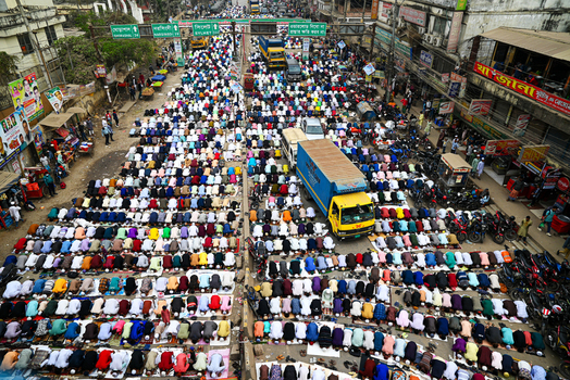 Tongi Bangladesh 31 January 2025 Aerial view of Tongi Ijtema Maidan with thousands of people gathered for prayer filling the streets with a truck and motorcycles visible.
