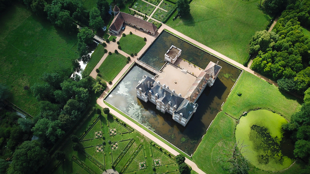 Aerial view of the historic Chateau de Cormatin surrounded by a wide moat and meticulously manicured formal gardens in Cormatin Bourgogne Franche Comte France. Aerial view of the historic Chateau de Cormatin surrounded by a wide moat and meticulously manicured formal gardens in Cormatin Bourgogne Franche Comte France.