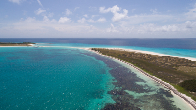 Aerial view of Los Roques archipelago featuring turquoise waters coral reefs and white sandy beaches under a clear blue sky in Los Roques Dependencias Federales Venezuela. Aerial view of Los Roques archipelago featuring turquoise waters coral reefs and white sandy beaches under a clear blue sky in Los Roques Dependencias Federales Venezuela.
