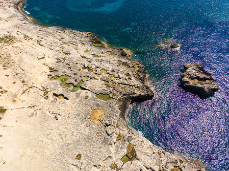 Aerial view of the rocky coastline and natural pools at Dwejra Bay with turquoise Mediterranean waters Gozo Region Malta. Aerial view of the rocky coastline and natural pools at Dwejra Bay with turquoise Mediterranean waters Gozo Region Malta.
