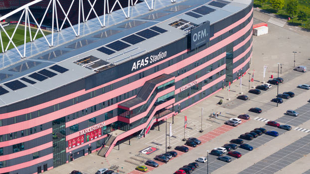 Alkmaar Netherlands 05 May 2026 Aerial view of the AFAS stadium with its modern red and black facade solar panels on the roof and a parking lot filled with cars on a sunny day.
