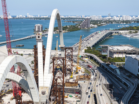 Aerial view of the vibrant contrast of the new bridge construction against the azure waters of Biscayne Bay and the distant Miami skyline Miami Florida USA. Aerial view of the vibrant contrast of the new bridge construction against the azure waters of Biscayne Bay and the distant Miami skyline Miami Florida USA.