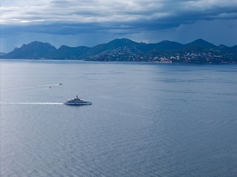 Aerial view of a luxury yacht cruising through the Mediterranean Sea near the coast of Ile Sainte Marguerite under a dramatic cloudy sky in Cannes Provence Alpes Cote d Azur France. Aerial view of a luxury yacht cruising through the Mediterranean Sea near the coast of Ile Sainte Marguerite under a dramatic cloudy sky in Cannes Provence Alpes Cote d Azur France.