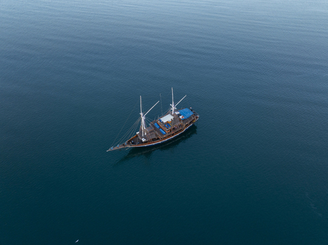 Aerial view of a traditional wooden phinisi boat sailing on the calm deep blue waters of the sea in Komodo East Nusa Tenggara Indonesia. Aerial view of a traditional wooden phinisi boat sailing on the calm deep blue waters of the sea in Komodo East Nusa Tenggara Indonesia.