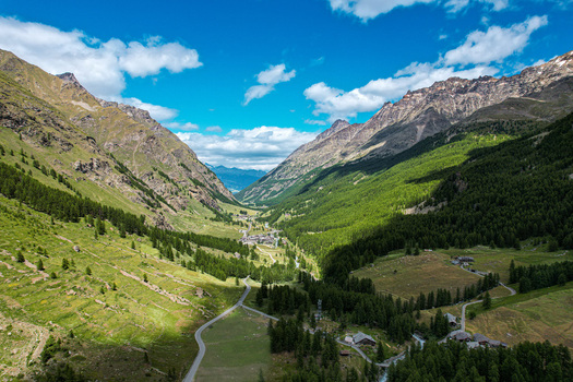 Aerial view of the village of Rhemes Notre Dame nestled in a lush green alpine valley surrounded by steep mountain slopes and dense pine forests Rhemes Notre Dame Valle d Aosta Italy. Aerial view of the village of Rhemes Notre Dame nestled in a lush green alpine valley surrounded by steep mountain slopes and dense pine forests Rhemes Notre Dame Valle d Aosta Italy.