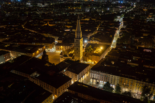 Aerial view of the illuminated Modena Cathedral and the Ghirlandina tower at night surrounded by the historic urban fabric of the city center in Modena Emilia Romagna Italy.
