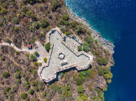 Aerial view of The Castle of Porto Palermo a historic triangular fortress on a rocky peninsula surrounded by dense vegetation and blue Ionian Sea in Porto Palermo Albania.