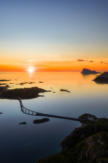 Aerial view of Sommaroy bridge connecting islands in the Arctic landscape during a vibrant sunset with calm waters and rocky coastlines in Sommaroy Troms Norway. Aerial view of Sommaroy bridge connecting islands in the Arctic landscape during a vibrant sunset with calm waters and rocky coastlines in Sommaroy Troms Norway.