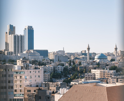 View of the Amman skyline featuring modern skyscrapers and the blue dome of the King Abdullah I Mosque under a clear sky in Amman Amman Governorate Jordan.