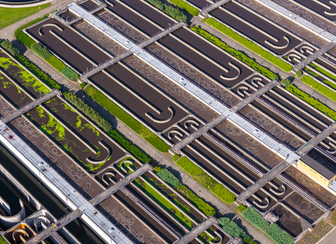 Aerial view of a waste water treatment plant featuring large aeration tanks concrete walkways and green landscaping in Poland. Aerial view of a waste water treatment plant featuring large aeration tanks concrete walkways and green landscaping in Poland.