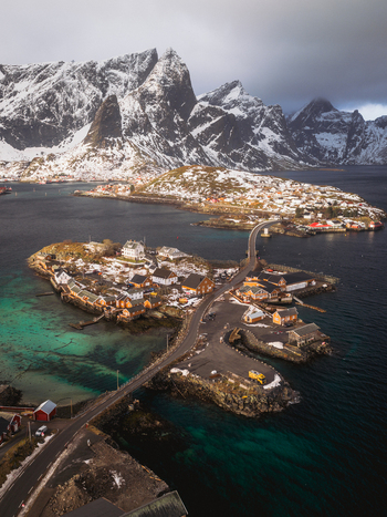 Aerial view of the quaint village nestled on Sakris&oslash;ya island connected by bridge with snow dusted mountains rising in the background Sakris&oslash;ya Nordland Norway.