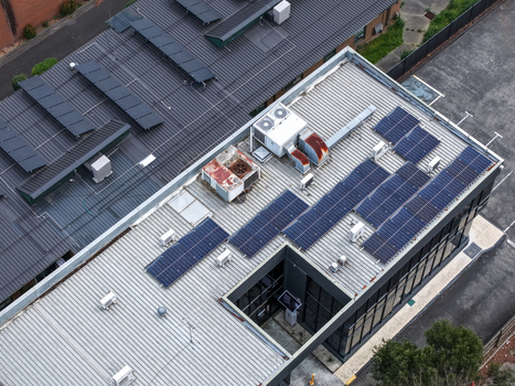 Melbourne VIC Australia 25 September 2026 Aerial view of a commercial building roof featuring numerous solar panels HVAC units and corrugated metal surfaces in an industrial area.