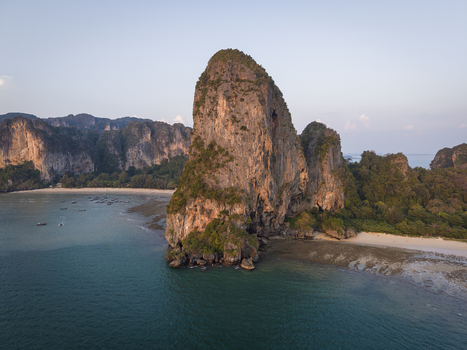 Aerial view of monolithic limestone cliffs jutting from the turquoise sea fringed by beaches and lush greenery Railay Beach Thailand.