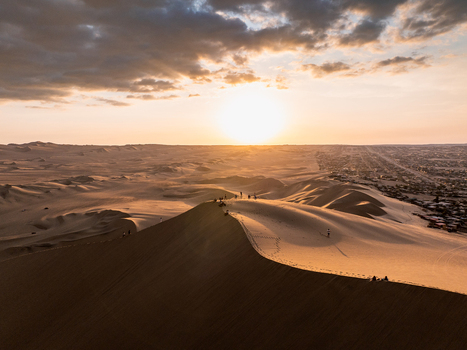 Aerial view of Huacachina sand dunes at sunset with golden light illuminating the desert landscape and the nearby town in Huacachina Ica Peru. Aerial view of Huacachina sand dunes at sunset with golden light illuminating the desert landscape and the nearby town in Huacachina Ica Peru.