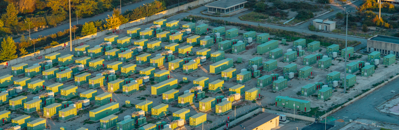 Aerial view of modular battery storage containers and electrical equipment at a modern energy facility illuminated by warm evening sunlight Italy. Aerial view of modular battery storage containers and electrical equipment at a modern energy facility illuminated by warm evening sunlight Italy.