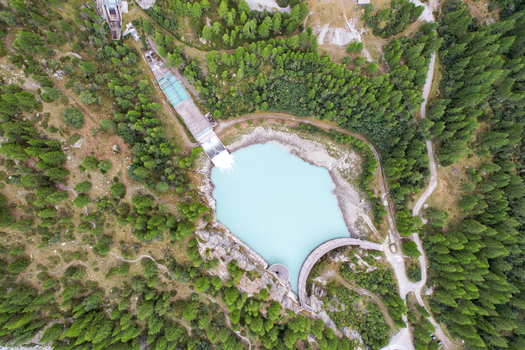Aerial view of Barrage de Ferpecle with its turquoise reservoir surrounded by dense pine forests and rugged mountain terrain in Evolene Valais Switzerland. Aerial view of Barrage de Ferpecle with its turquoise reservoir surrounded by dense pine forests and rugged mountain terrain in Evolene Valais Switzerland.