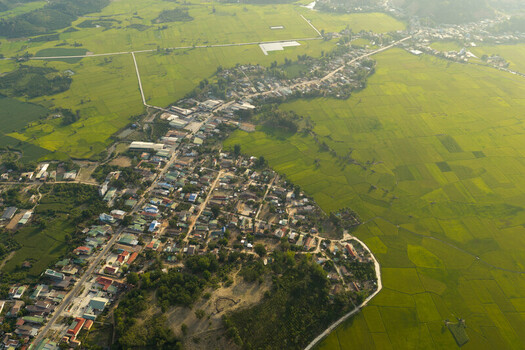 Aerial view of Lak Lake surrounded by lush green rice paddies and residential rooftops in Lien Son Lak Dak Lak Vietnam. Aerial view of Lak Lake surrounded by lush green rice paddies and residential rooftops in Lien Son Lak Dak Lak Vietnam.