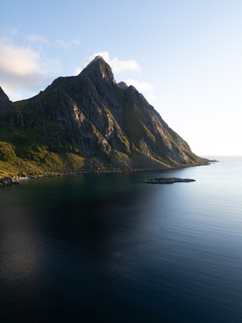 Aerial view of the dramatic mountain peaks of Tangstad rising above the calm blue waters of the Norwegian Sea under a clear sky Leknes Nordland Norway. Aerial view of the dramatic mountain peaks of Tangstad rising above the calm blue waters of the Norwegian Sea under a clear sky Leknes Nordland Norway.