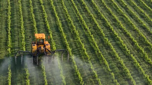 Aerial view of a yellow tractor spraying a vineyard France Aerial view of a yellow tractor spraying a vineyard France