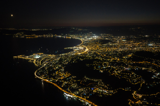 Aerial view of the illuminated coastline and city lights of Antibes at night featuring the crescent moon over the Mediterranean Sea in Antibes Provence Alpes Cote d Azur France. Aerial view of the illuminated coastline and city lights of Antibes at night featuring the crescent moon over the Mediterranean Sea in Antibes Provence Alpes Cote d Azur France.