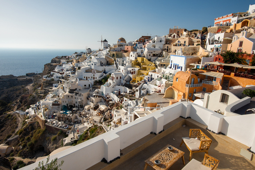 View of the white buildings and blue domed churches of Fira perched on the volcanic cliffs overlooking the Aegean Sea in Fira Greece. View of the white buildings and blue domed churches of Fira perched on the volcanic cliffs overlooking the Aegean Sea in Fira Greece.