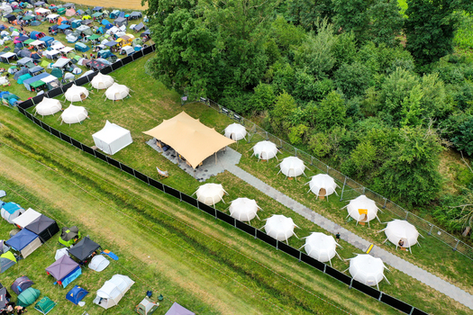 Herzogenaurach Germany 26 July 2025 Aerial view of the Open Beatz Festival glamping area featuring white dome tents and a large tan canopy tent near a lush forest.