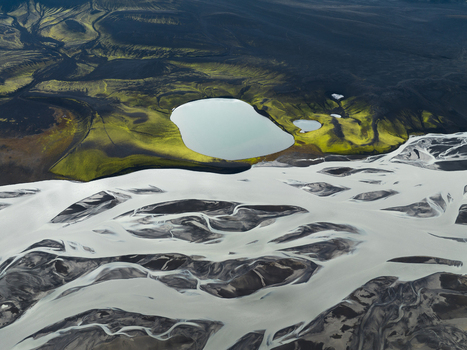 Aerial view of glacial rivers carving through volcanic ash and green moss creating a stark contrast of textures and colors Highlands Iceland.