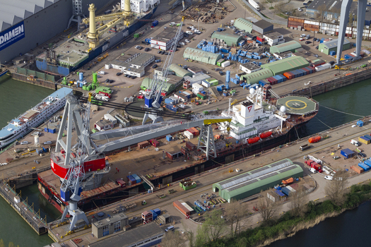 Aerial view of the industrial Rotterdam Harbour featuring a large crane a docked ship with a helipad and surrounding shipping containers in Rotterdam South Holland Netherlands. Aerial view of the industrial Rotterdam Harbour featuring a large crane a docked ship with a helipad and surrounding shipping containers in Rotterdam South Holland Netherlands.