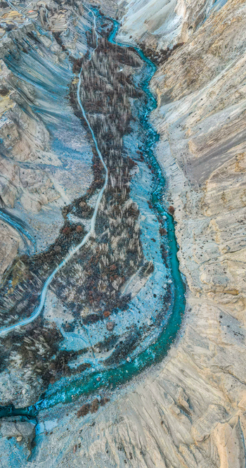 Aerial view of a turquoise river snaking through a rugged valley contrasting with the earthy tones of the arid landscape Hunza Nagar Gilgit Pakistan. Aerial view of a turquoise river snaking through a rugged valley contrasting with the earthy tones of the arid landscape Hunza Nagar Gilgit Pakistan.
