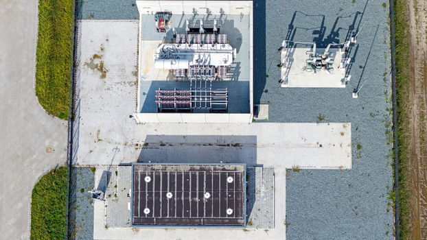 Aerial view of an electrical substation with transformers and switchgear equipment on concrete pads surrounded by gravel and green grass in Espel Flevoland Netherlands. Aerial view of an electrical substation with transformers and switchgear equipment on concrete pads surrounded by gravel and green grass in Espel Flevoland Netherlands.