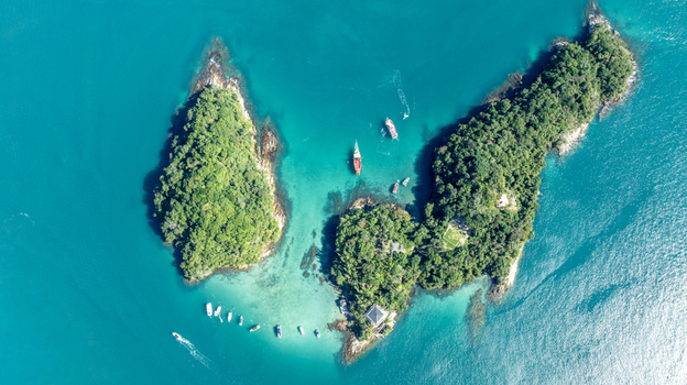Aerial view of Lagoa Azul with turquoise water lush green islands and small boats anchored in the bay in Angra dos Reis Rio de Janeiro Brazil.