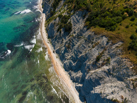 Aerial view of the dramatic Byala Cliffs meeting the turquoise waters of the Black Sea with lush green vegetation and a sandy beach in Byala Varna Bulgaria. Aerial view of the dramatic Byala Cliffs meeting the turquoise waters of the Black Sea with lush green vegetation and a sandy beach in Byala Varna Bulgaria.