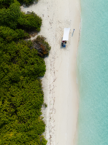 Aerial view of the white sandy beach meeting the turquoise water with a lone canopy standing under the sun Thuraakunu Thiladhunmathee Uthuruburi Maldives. Aerial view of the white sandy beach meeting the turquoise water with a lone canopy standing under the sun Thuraakunu Thiladhunmathee Uthuruburi Maldives.