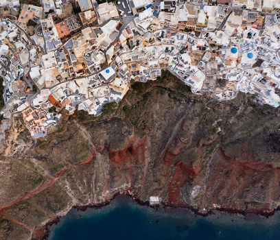 Aerial view of the iconic white washed buildings cascading down the dramatic volcanic cliffs into the deep blue Aegean Sea Fira Thira Greece. Aerial view of the iconic white washed buildings cascading down the dramatic volcanic cliffs into the deep blue Aegean Sea Fira Thira Greece.