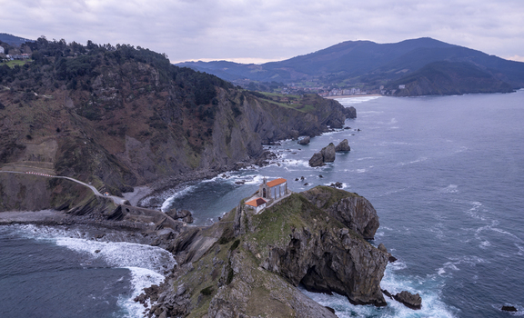 Aerial view of San Juan de Gaztelugatxe a historic hermitage on a rocky islet connected by a winding stone bridge to the rugged coastline in Gaztelugatxeko Doniene Euskadi Spain.