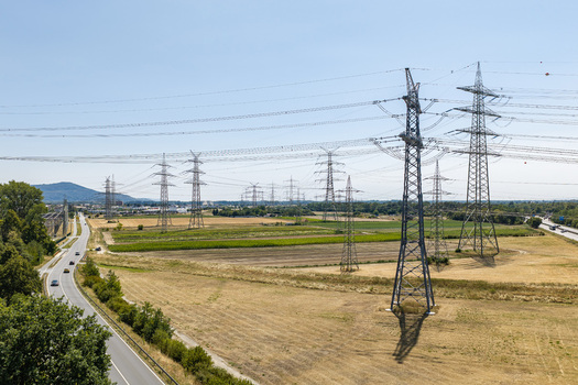 Aerial view of the Amprion Umspannwerk power substation with high voltage transmission towers and power lines crossing agricultural fields near a road in Pfungstadt Hessen Germany.