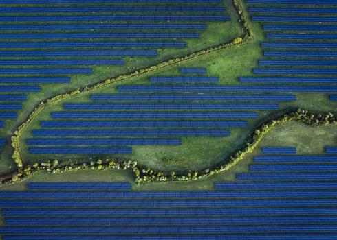 Aerial view of Gillinstown Solar Farm with rows of blue photovoltaic panels and a winding green path County Meath Ireland.