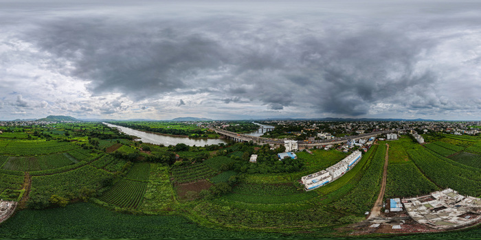 Aerial view of the Krishna River flowing through lush green agricultural fields and the cityscape of Karad with a bridge under a cloudy sky in Karad Maharashtra India. Aerial view of the Krishna River flowing through lush green agricultural fields and the cityscape of Karad with a bridge under a cloudy sky in Karad Maharashtra India.