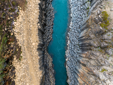 Aerial view of the turquoise river flowing through the dramatic basalt columns of Studlagil Canyon in Iceland. Aerial view of the turquoise river flowing through the dramatic basalt columns of Studlagil Canyon in Iceland.