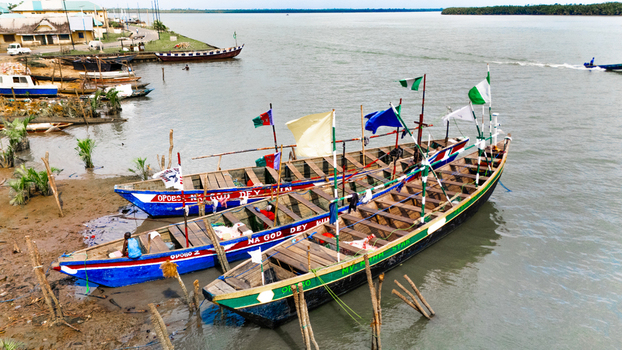 Aerial view of traditional wooden boats moored along the muddy riverbank in Rivers Nigeria.