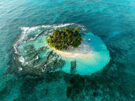 Aerial view of Guyam Island featuring a small tropical island with lush palm trees white sand beach and clear turquoise water surrounded by coral reefs in General Luna Caraga Philippines. Aerial view of Guyam Island featuring a small tropical island with lush palm trees white sand beach and clear turquoise water surrounded by coral reefs in General Luna Caraga Philippines.