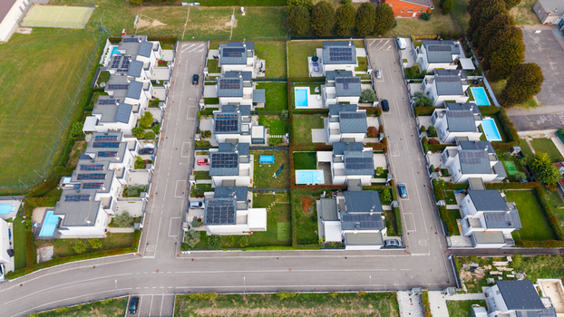 Aerial view of modern residential houses with private gardens swimming pools and solar panels on rooftops in a suburban neighborhood in Milan Lombardy Italy.