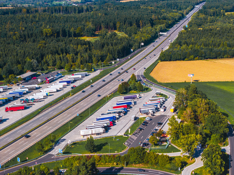 Aerial view of Logistikzentrum Allhaming with numerous trucks parked in the logistics facility adjacent to a highway surrounded by forest and fields in Allhaming Oberosterreich Austria. Aerial view of Logistikzentrum Allhaming with numerous trucks parked in the logistics facility adjacent to a highway surrounded by forest and fields in Allhaming Oberosterreich Austria.