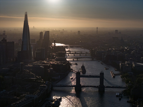 Aerial view of Tower Bridge and The Shard silhouetted against the golden hour sun over the River Thames and the hazy city skyline London Greater London United Kingdom. Aerial view of Tower Bridge and The Shard silhouetted against the golden hour sun over the River Thames and the hazy city skyline London Greater London United Kingdom.