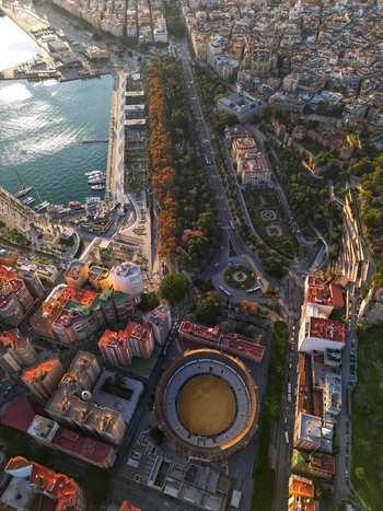 Aerial view of the Plaza de toros de La Malagueta bullring the lush city park and the harbor area under warm sunlight in Malaga Andalusia Spain. Aerial view of the Plaza de toros de La Malagueta bullring the lush city park and the harbor area under warm sunlight in Malaga Andalusia Spain.
