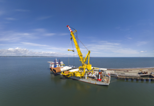 Aerial view of a large yellow crane ship loading wind turbine components at the Port of Leith under a clear blue sky Edinburgh Scotland United Kingdom. Aerial view of a large yellow crane ship loading wind turbine components at the Port of Leith under a clear blue sky Edinburgh Scotland United Kingdom.