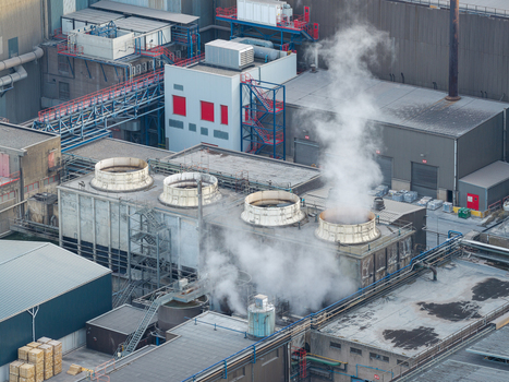 Aerial view of the industrial facility at Haven Genk with cooling towers emitting steam surrounded by steel production infrastructure and manufacturing buildings in Genk Vlaanderen Belgium.