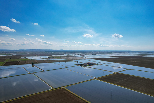 Aerial view of Azienda Agricola Veneria surrounded by flooded rice fields reflecting the blue sky and clouds in Veneria Piemonte Italy. Aerial view of Azienda Agricola Veneria surrounded by flooded rice fields reflecting the blue sky and clouds in Veneria Piemonte Italy.