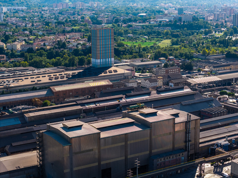 Aerial view of Acciai Speciali Terni S.p.A. steelworks facility featuring large industrial buildings with metallic roofs and a prominent tower in Terni Umbria Italy.