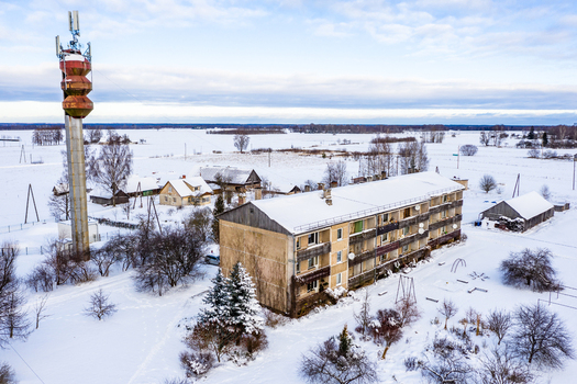 Aerial view of a residential apartment building and a tall communication tower in a snow covered rural landscape Latvia. Aerial view of a residential apartment building and a tall communication tower in a snow covered rural landscape Latvia.
